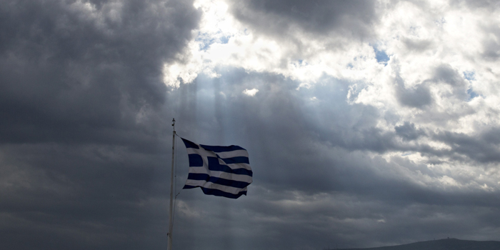 A Greek flag waves as the sun's rays shine through clouds at the ancient Acropolis hill, in Athens, Monday June 22, 2015. A top European Union official said that debt talks between Greece and its international creditors have made some progress but that a deal to avoid potential bankruptcy remains elusive. (AP Photo/Petros Giannakouris)